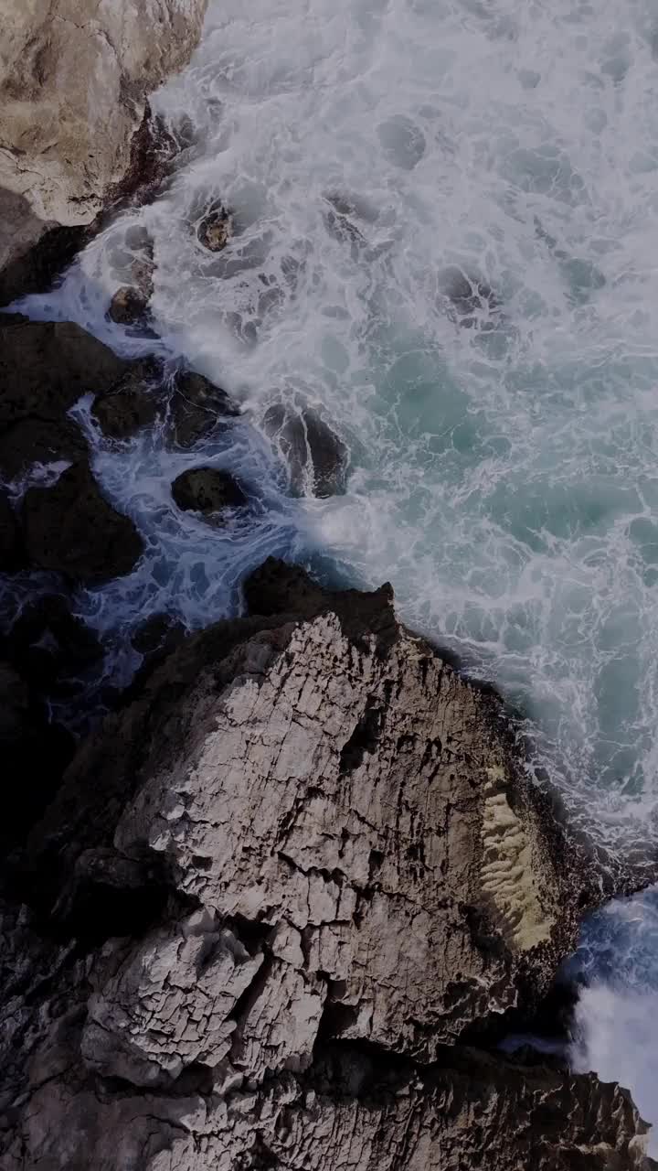 鸟瞰图的海浪冲击悬崖在金丘海滩，卡斯凯伊斯，葡萄牙。垂直视频视频素材