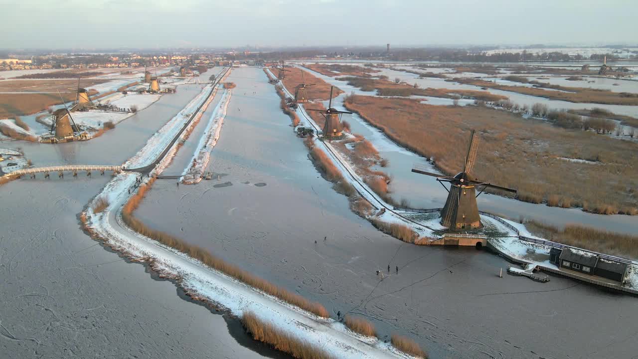 荷兰，白雪覆盖的风车和结冰的运河鸟瞰图。视频素材