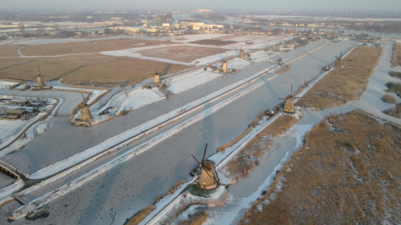 荷兰，白雪覆盖的风车和结冰的河流鸟瞰图。视频素材