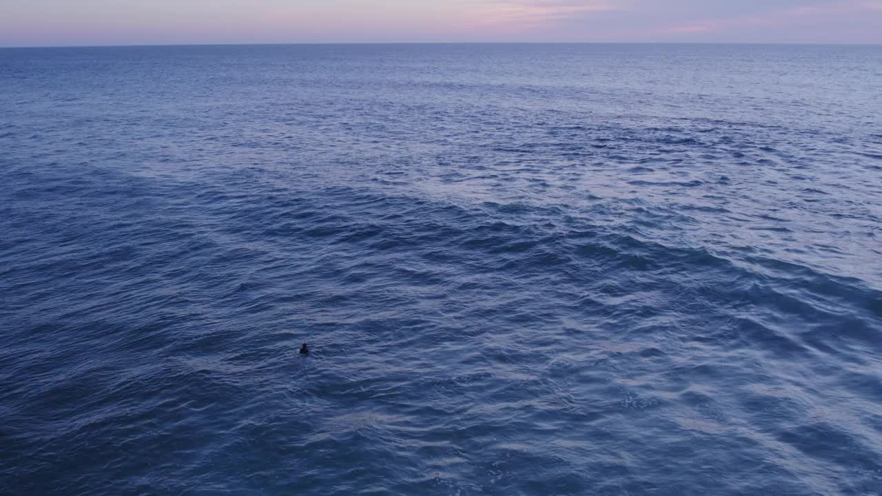 与冲浪者一起鸟瞰海浪上的日落，葡萄牙。视频素材