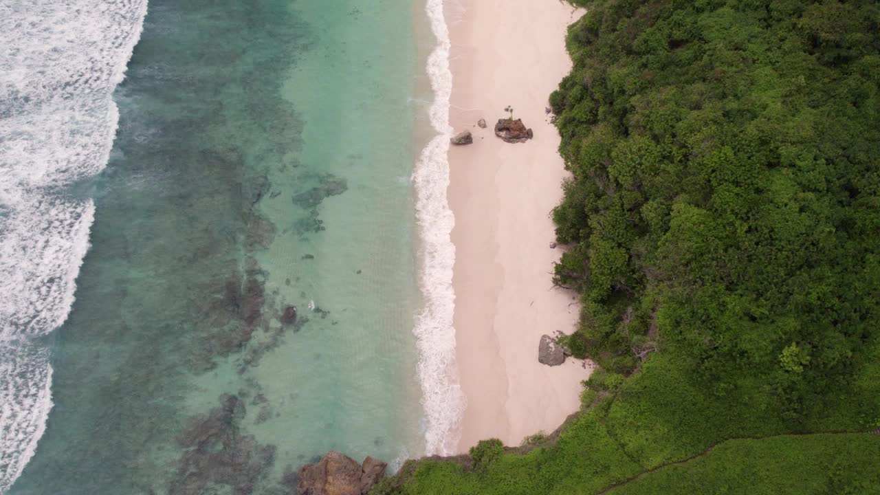 鸟瞰僻静的海滩与海浪，岩石和悬崖，印度尼西亚。视频素材