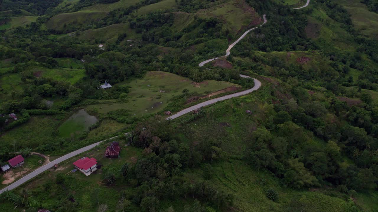 鸟瞰日落时葱郁的山丘和蜿蜒的道路，印度尼西亚。视频素材