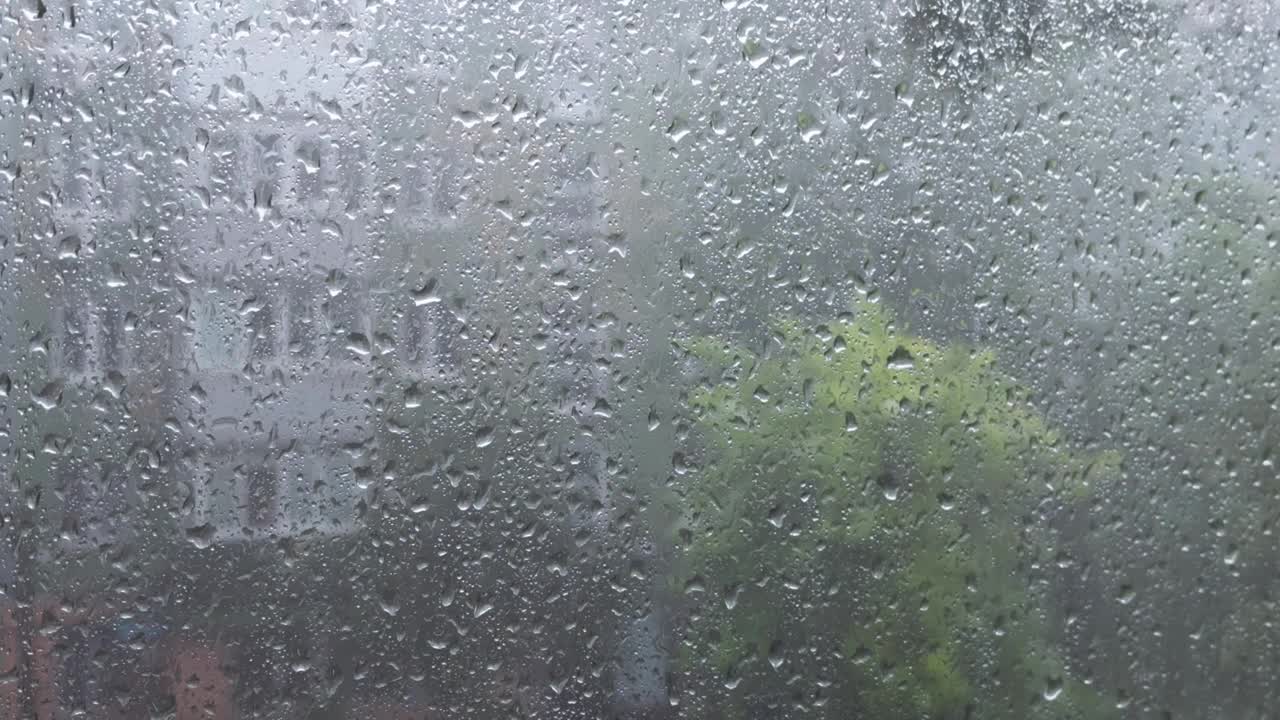 下雨时从窗户玻璃上流下的水滴。视频下载