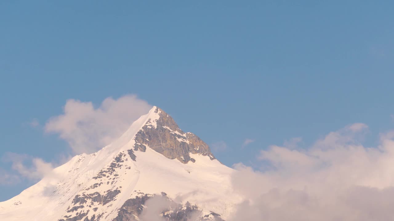 从印度喜马偕尔邦拉胡尔的康萨尔村看到的白雪皑皑的盖潘山顶上的橙色云的4K延时拍摄。日落时，云在山顶上翻滚。自然的晚上视频素材