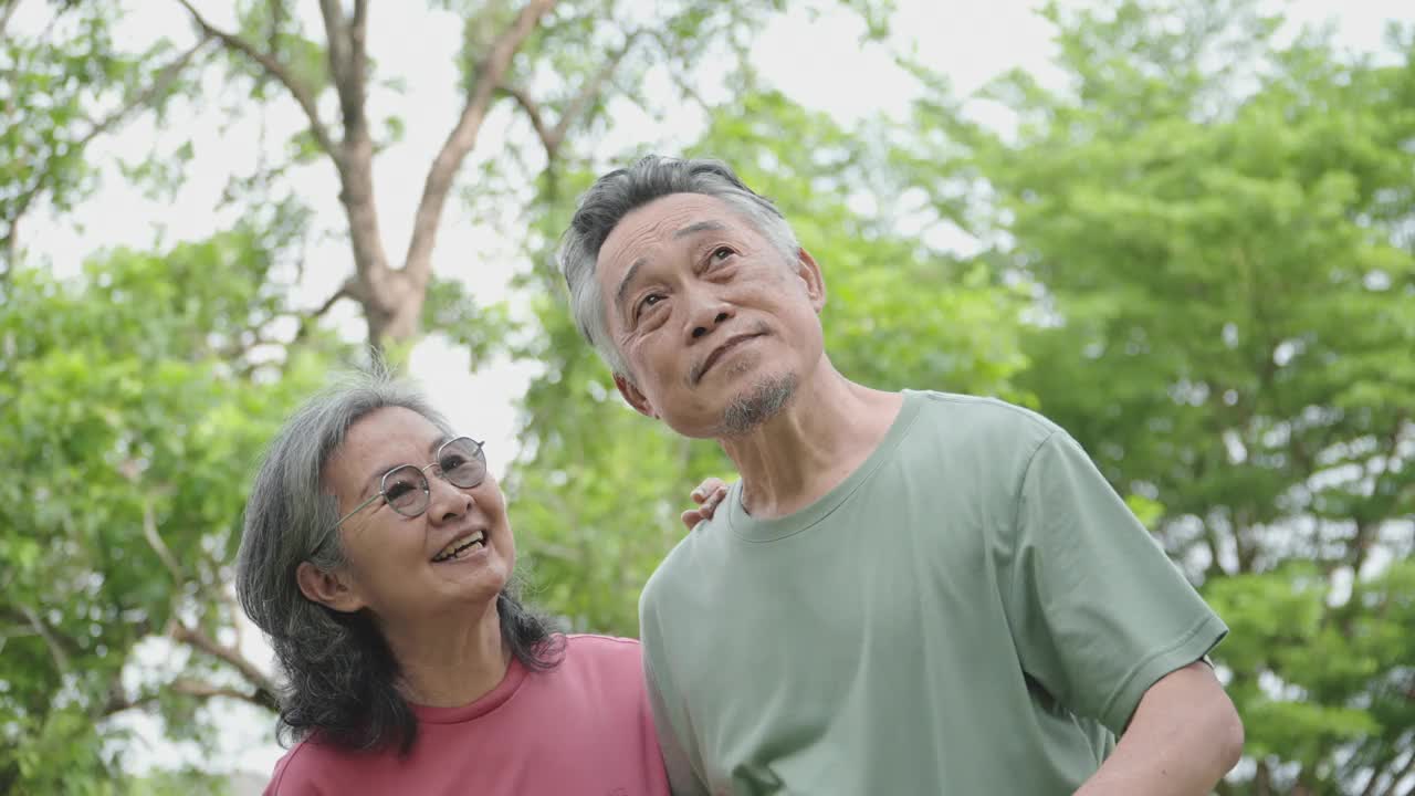 一名老年男子和一名亚洲女子在花园里用智能手机自拍。视频下载