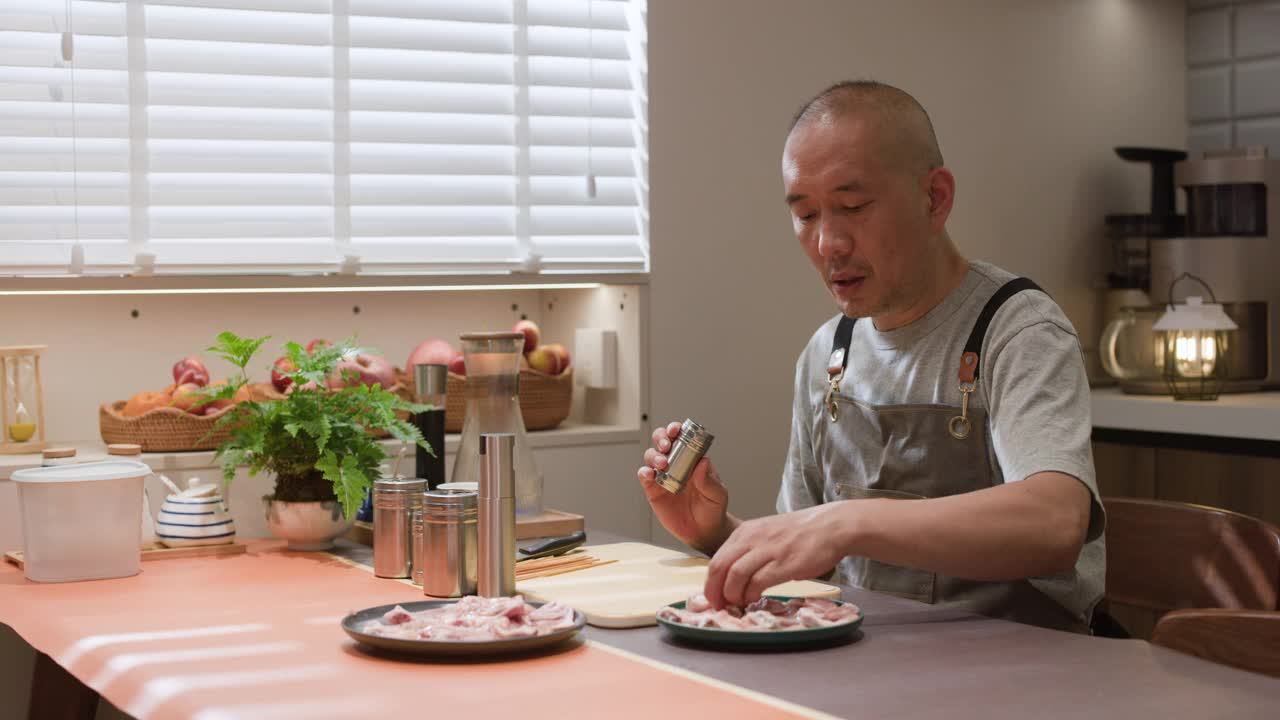 一位亚洲中年男子正在厨房准备食物视频下载