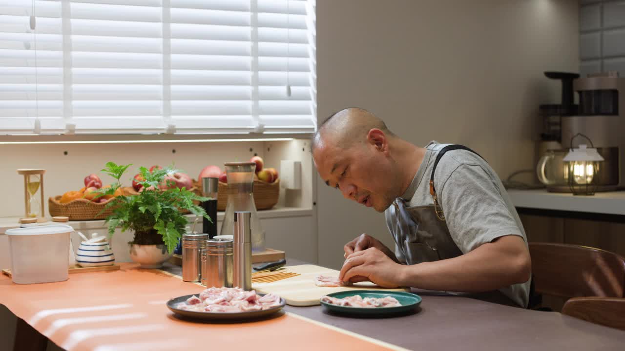 一位亚洲中年男子正在厨房准备食物视频素材