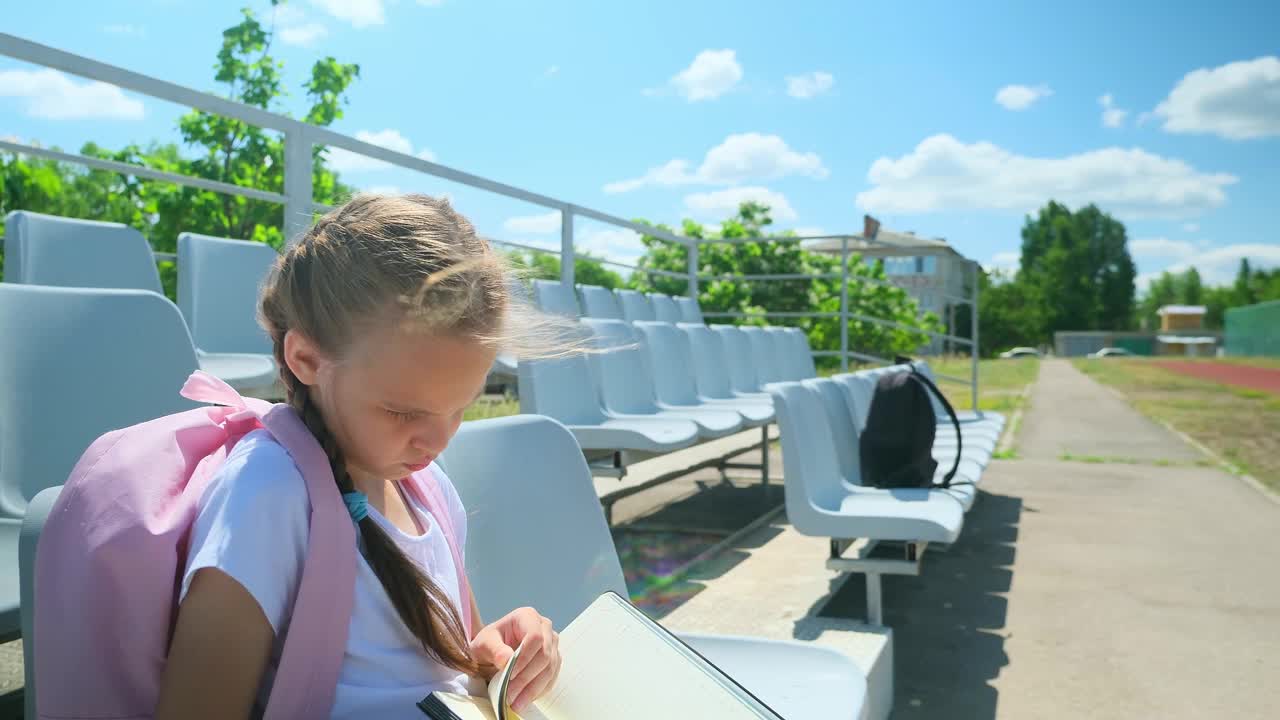 小女孩正在阅读课文，学习备课。女生做作业、学习、小学生在校园里，孩子独自集中学习聪明的课本知识视频素材