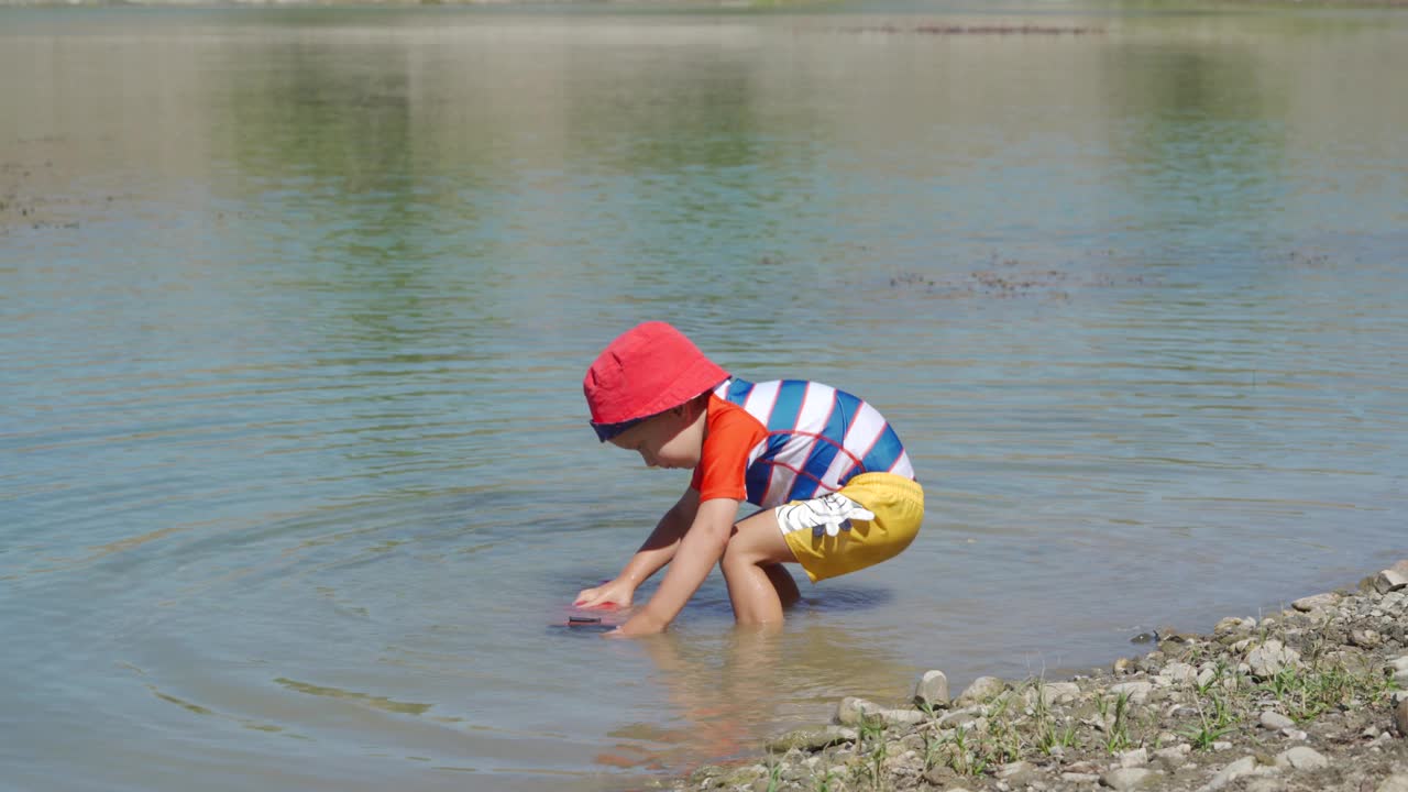 夏日里，穿着防晒服的小孩在湖边玩耍。视频素材