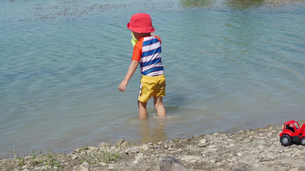 夏日里，穿着防晒服的小孩在湖边玩耍。视频素材