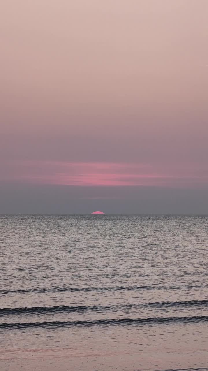 海滩日出半太阳出现在地平线上。海洋日落视图垂直镜头。视频下载