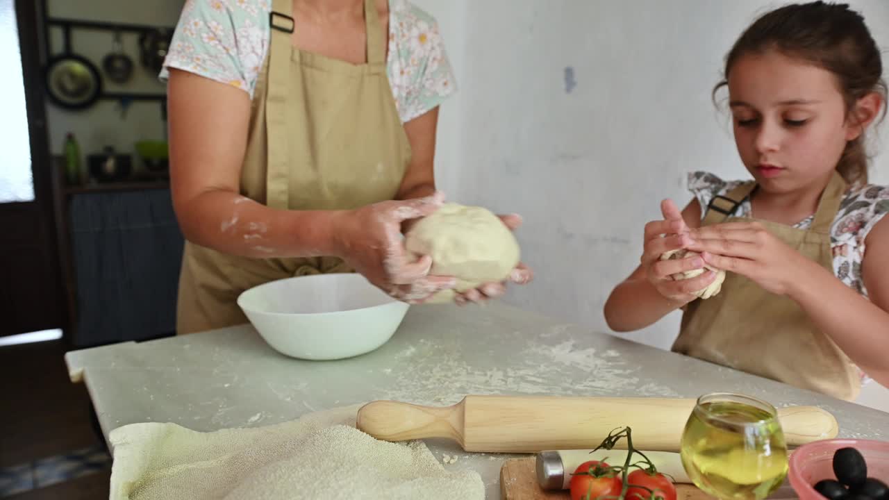 母女俩一起自制披萨面团。在厨房里进行家庭活动。视频素材