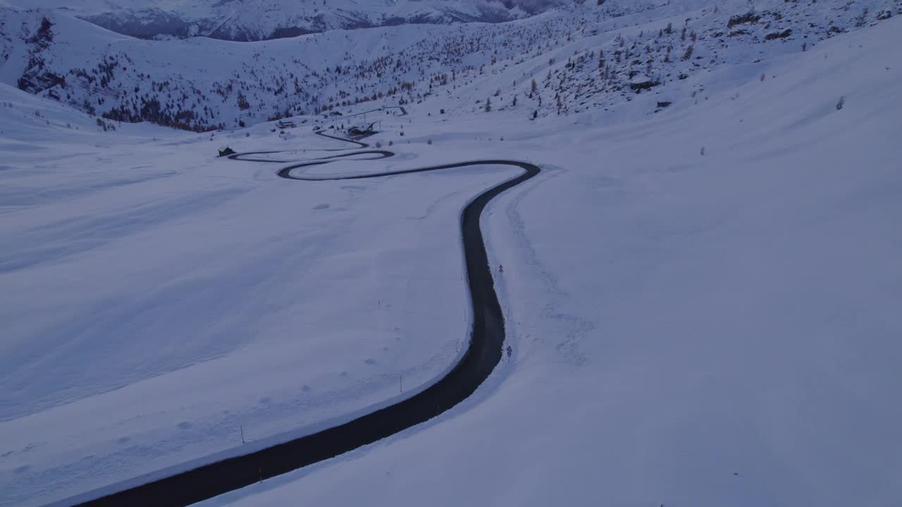 鸟瞰日落时分穿过雪山的蜿蜒道路，意大利。视频素材