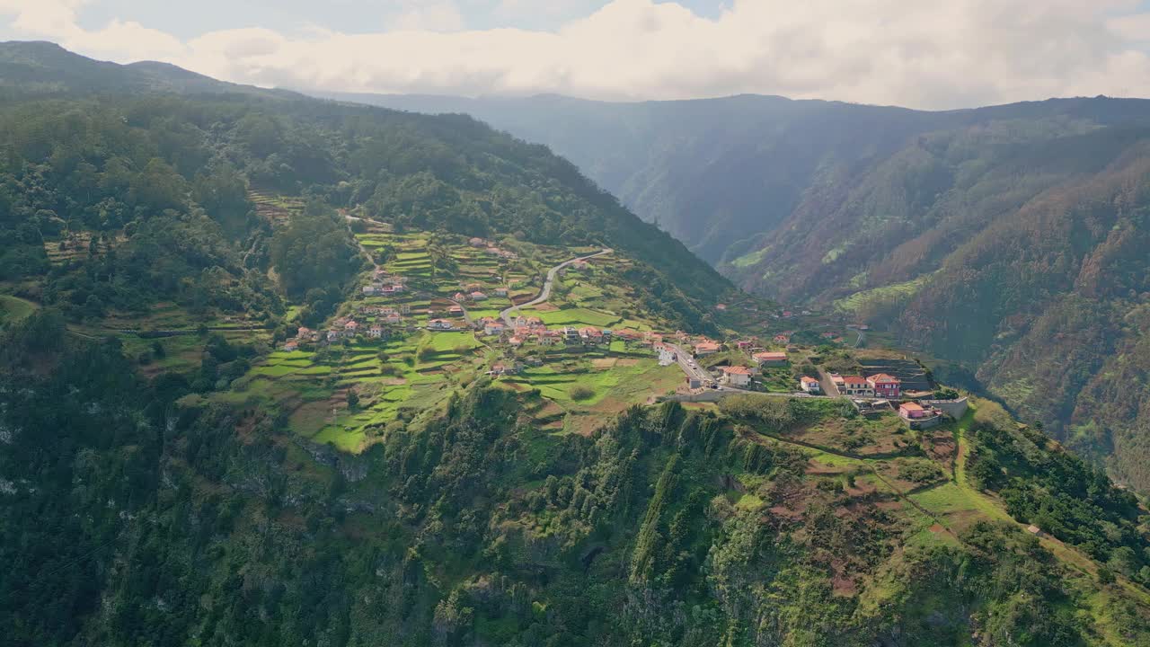 舒适的村庄坐落在绿色的山坡周围，鸟瞰宁静的景观。视频素材