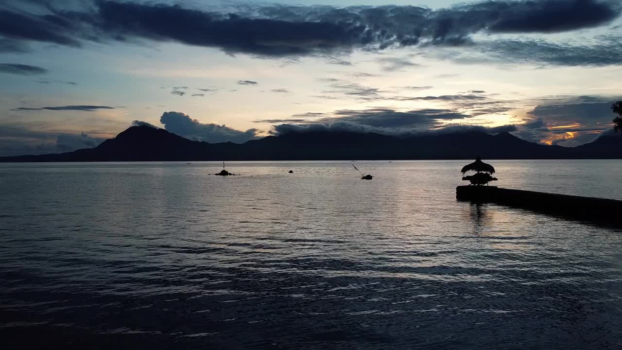 海面上的黎明映衬着热带山脉和云层视频素材