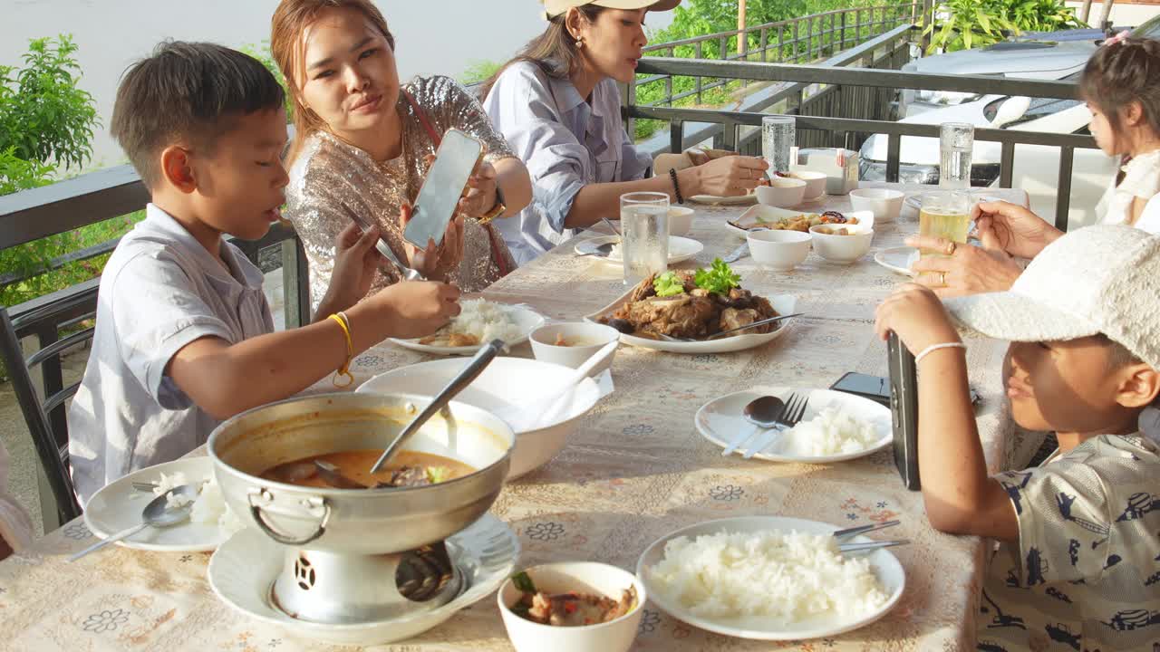 几个亚洲家庭成员在河边的一家户外餐厅愉快地一起享用晚餐。视频素材