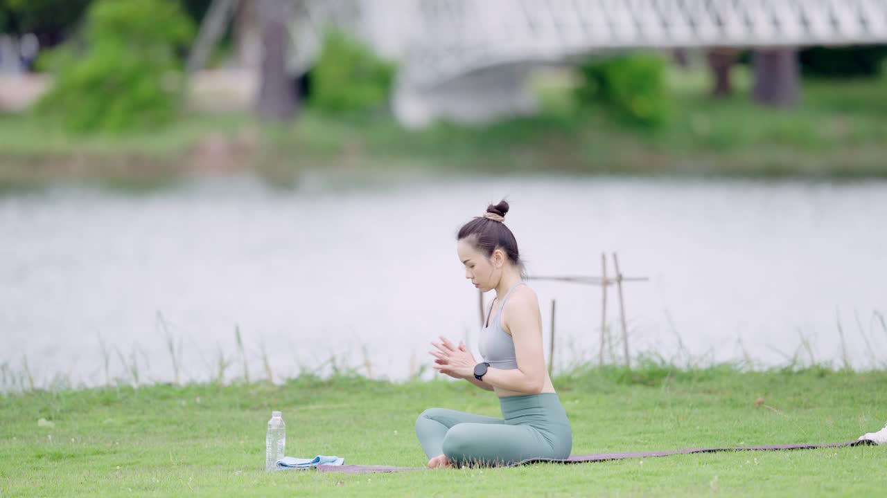 一个女人坐在水边的草地上视频素材