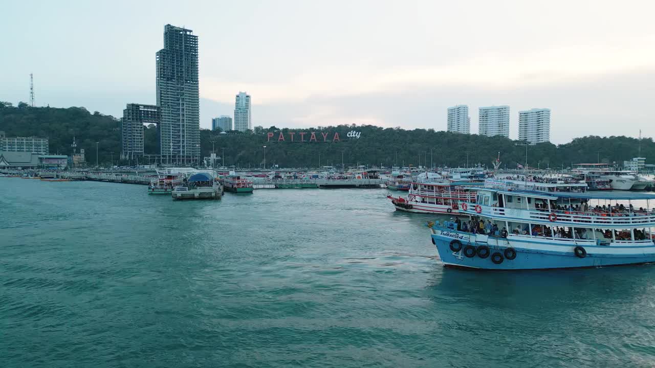 夕阳下的芭堤雅城市标志和芭堤雅快艇码头的4K无人机视图。视频素材