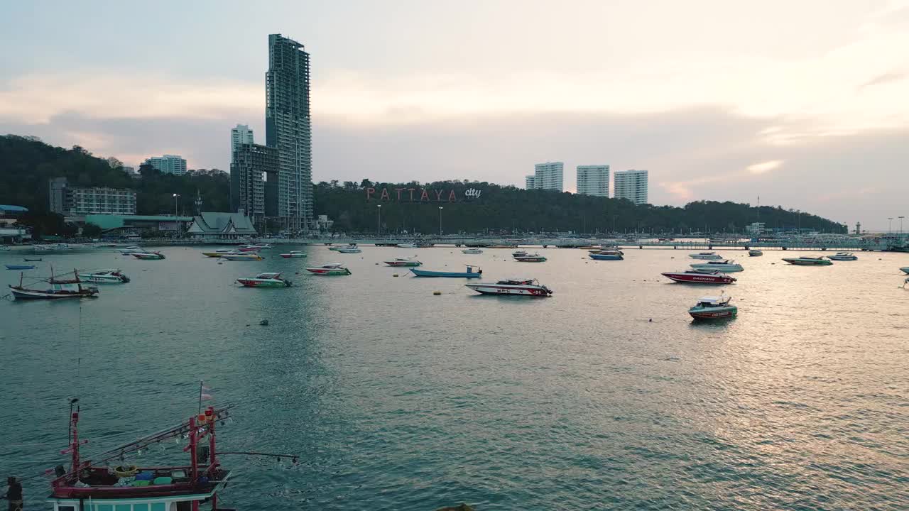 夕阳下的芭堤雅城市标志和芭堤雅快艇码头的4K无人机视图。视频下载