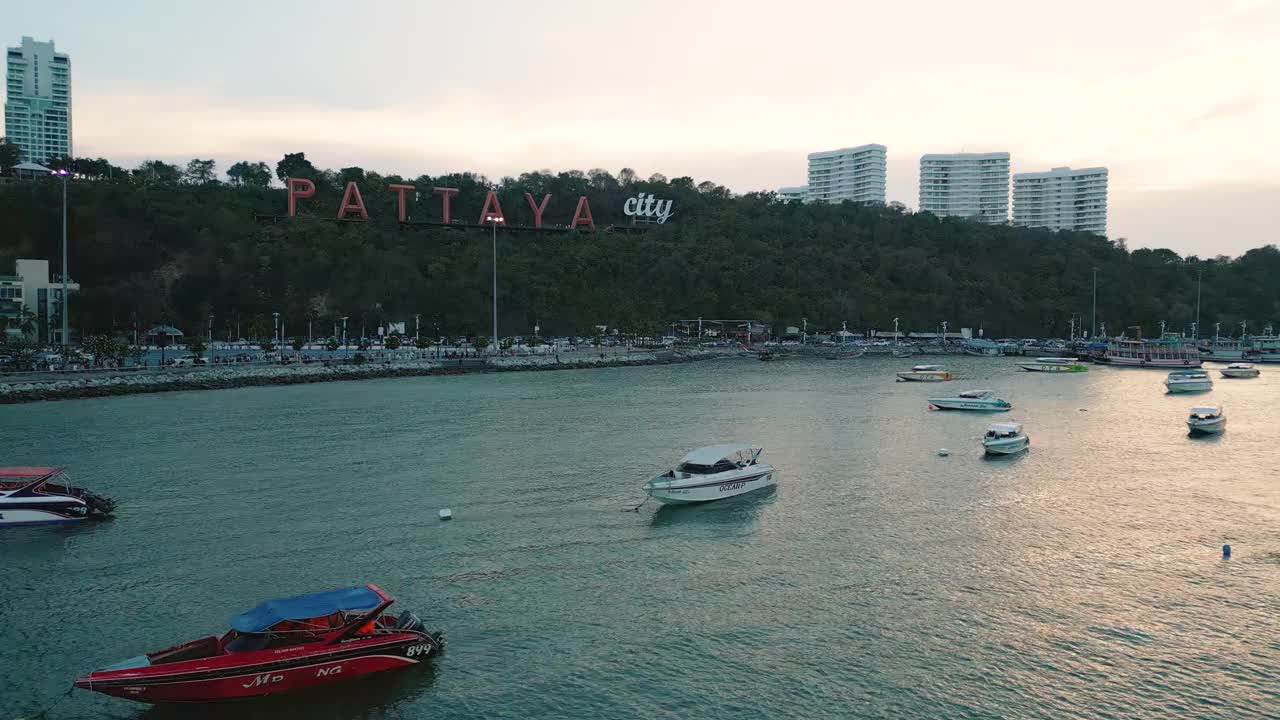 夕阳下的芭堤雅城市标志和芭堤雅快艇码头的4K无人机视图。视频下载