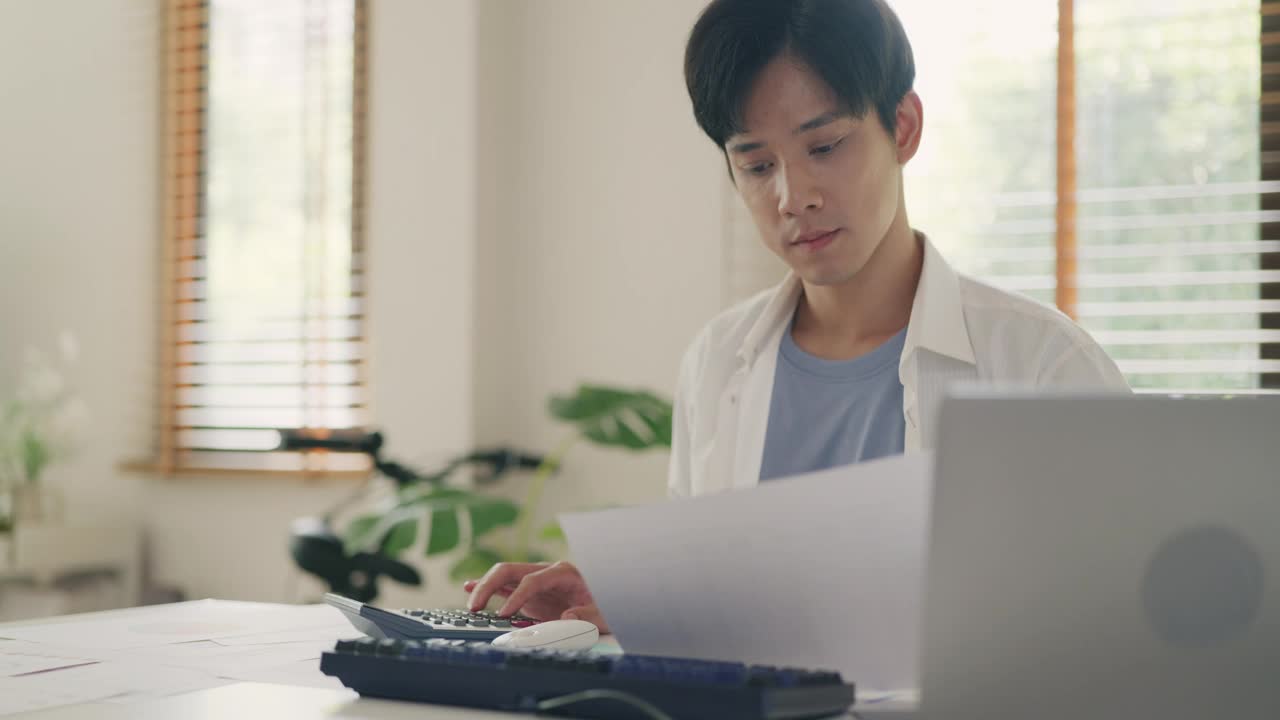 年轻的亚洲男子在家计算预算。视频素材