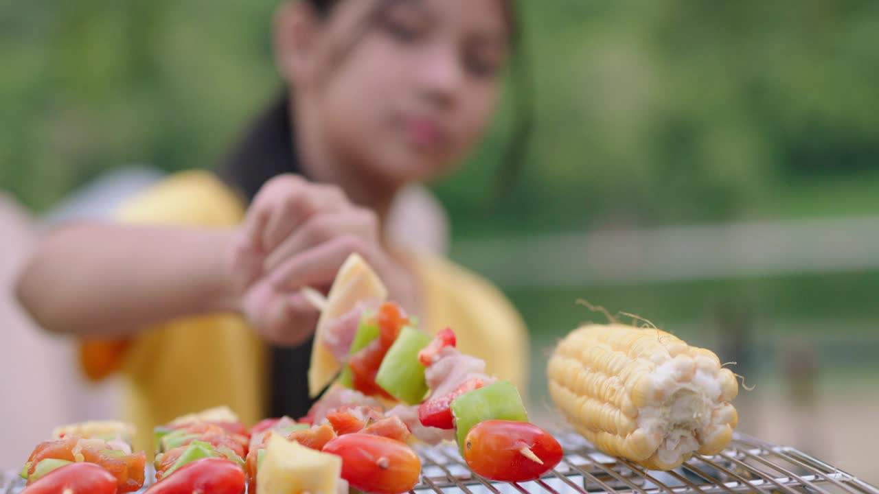 假期，亚洲爷爷、奶奶、孙女一起露营，一起在户外愉快地烧烤视频素材