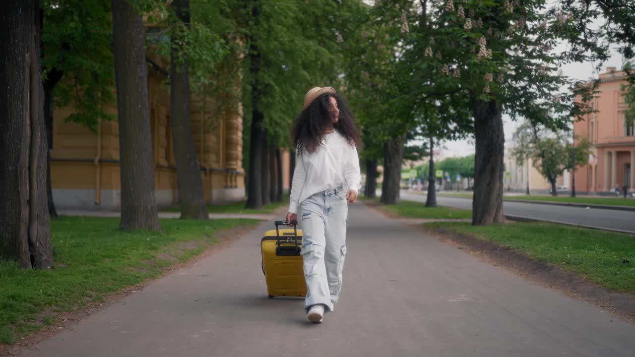 阿拉伯女学生暑假旅游，在街上滚动箱子。美丽高大的西班牙女士独自漫步在市中心的肖像，旅游观光，全身拍摄，游客视频素材