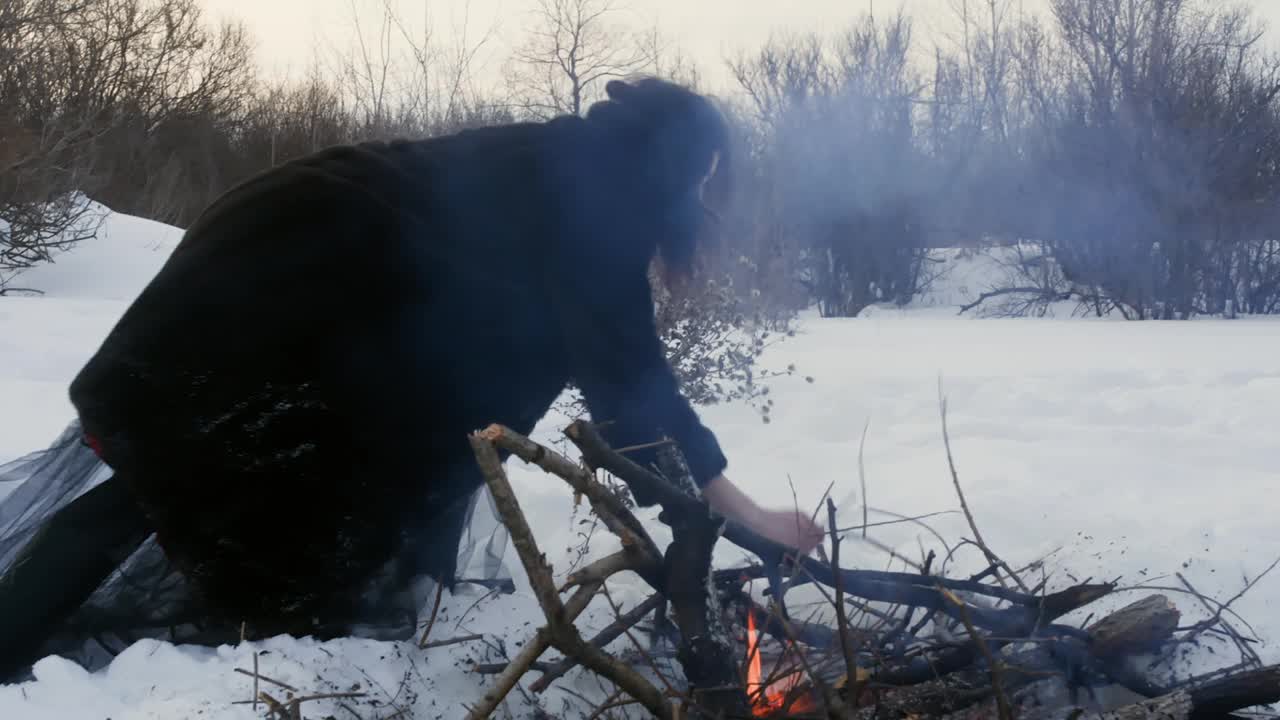 冬天，一名妇女在森林里的雪景中生火视频素材