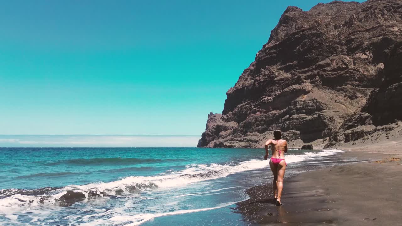 一个女人在大加那利岛未受破坏的处女海滩放松放松的田园诗般的场景视频下载