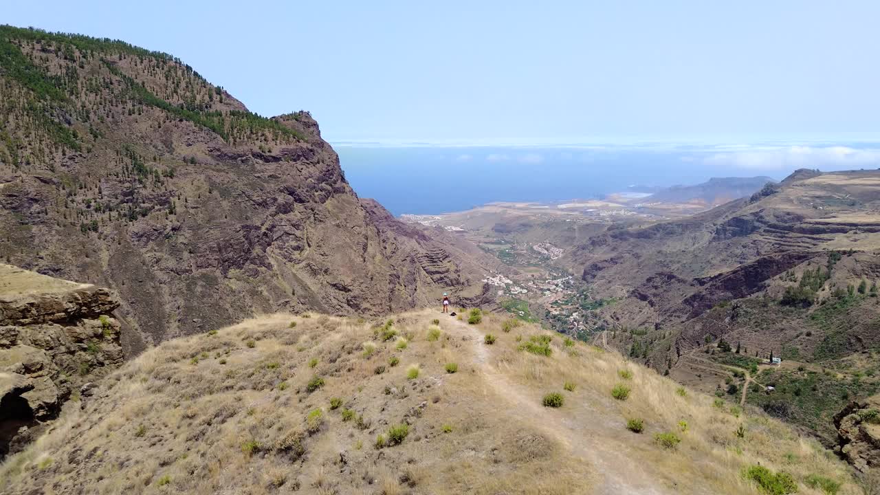 山顶上的旅游女孩张开双臂，用无人机鸟瞰大加那利岛的山谷和风景视频下载