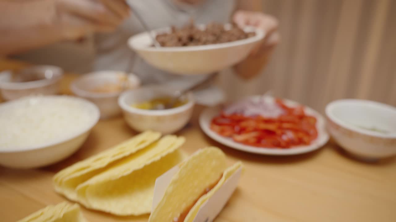 一名妇女在玉米饼壳里加入碎肉，准备美味的自制玉米饼。视频素材