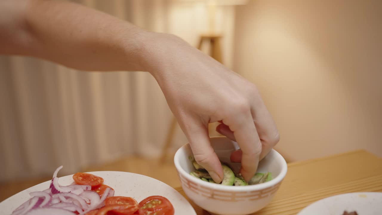 女人把鳄梨片加到墨西哥卷饼壳上，准备一个新鲜美味的墨西哥卷饼。视频素材