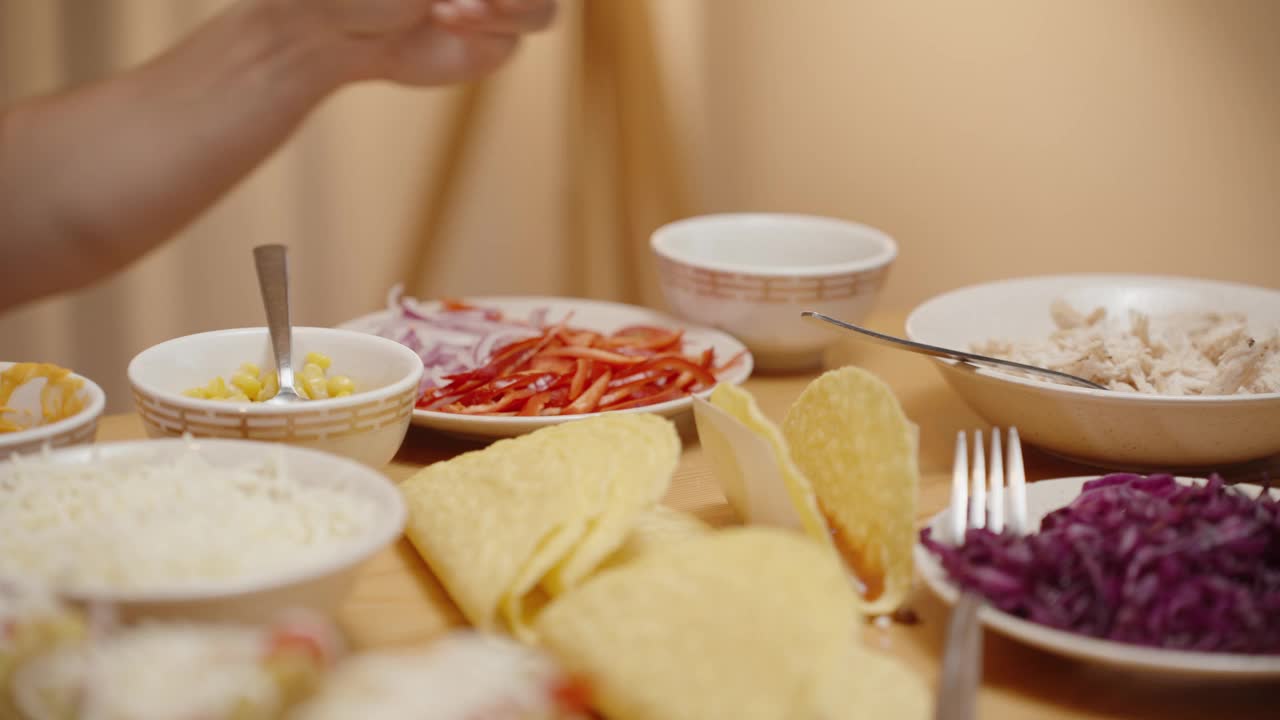 女人把鸡肉撒在墨西哥卷饼的外壳上，做成美味的馅料。视频素材