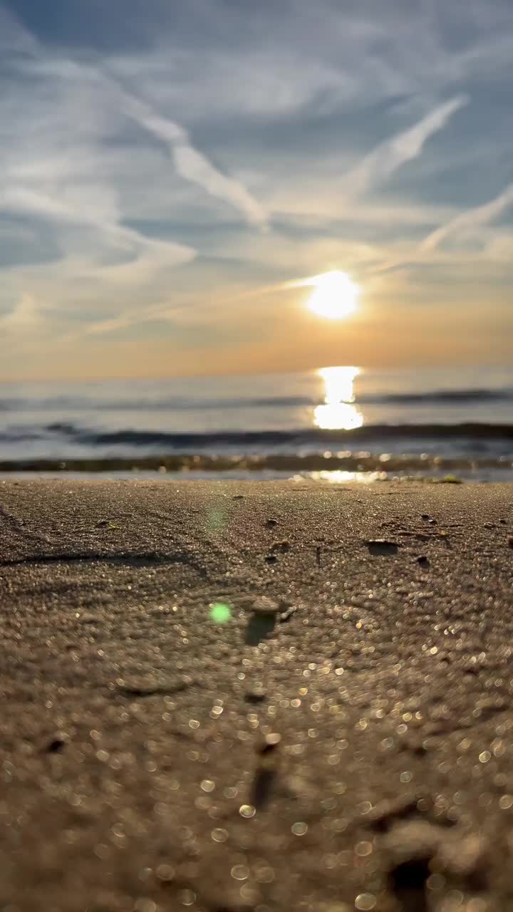 橙色的夕阳天空与云彩的背景下，海浪和海岸。鼓舞人心的平静的大海与日出的天空。水面上五颜六色的地平线。波浪的缓慢运动。垂直视频视频下载