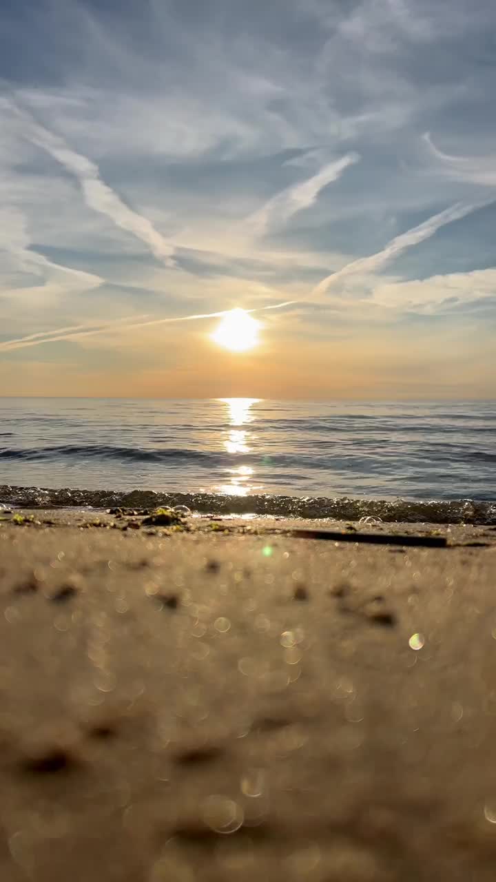 橙色的夕阳天空与云彩的背景下，海浪和海岸。鼓舞人心的平静的大海与日出的天空。水面上五颜六色的地平线。波浪的缓慢运动。垂直视频视频下载