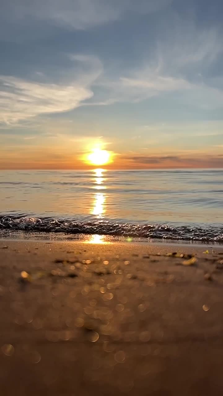 橙色的夕阳天空与云彩的背景下，海浪和海岸。鼓舞人心的平静的大海与日出的天空。水面上五颜六色的地平线。波浪的缓慢运动。垂直视频视频下载