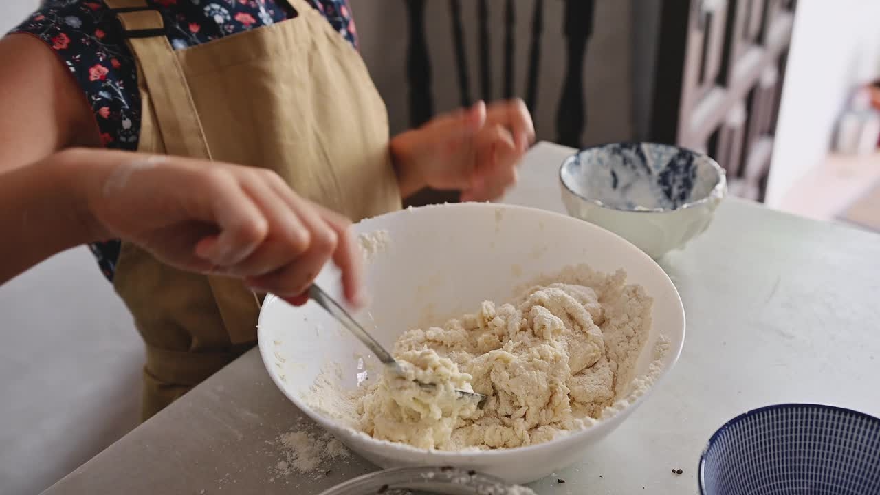 戴着围裙的小女孩在厨房里揉面视频素材