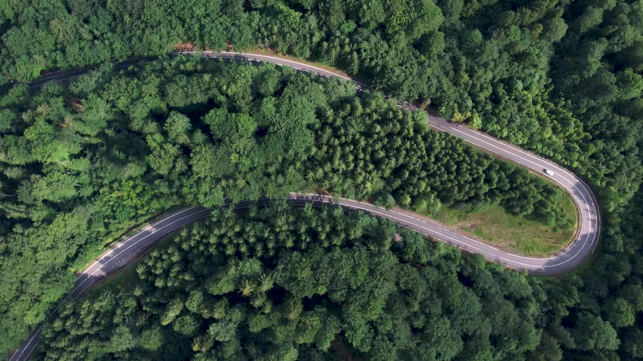 弯弯曲曲的柏油路上山林夏日。
鸟瞰图的道路穿过山和绿色的森林。视频素材