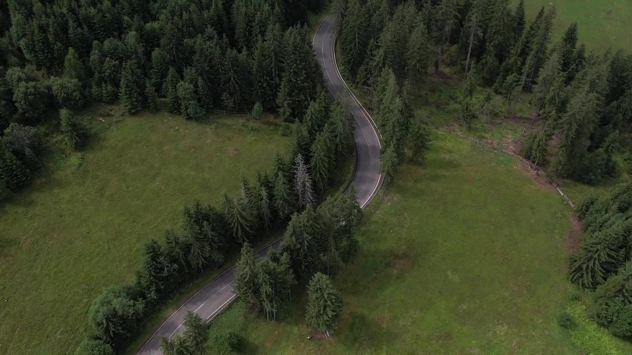 弯弯曲曲的柏油路上山林夏日。
鸟瞰图的道路穿过山和绿色的森林。视频下载