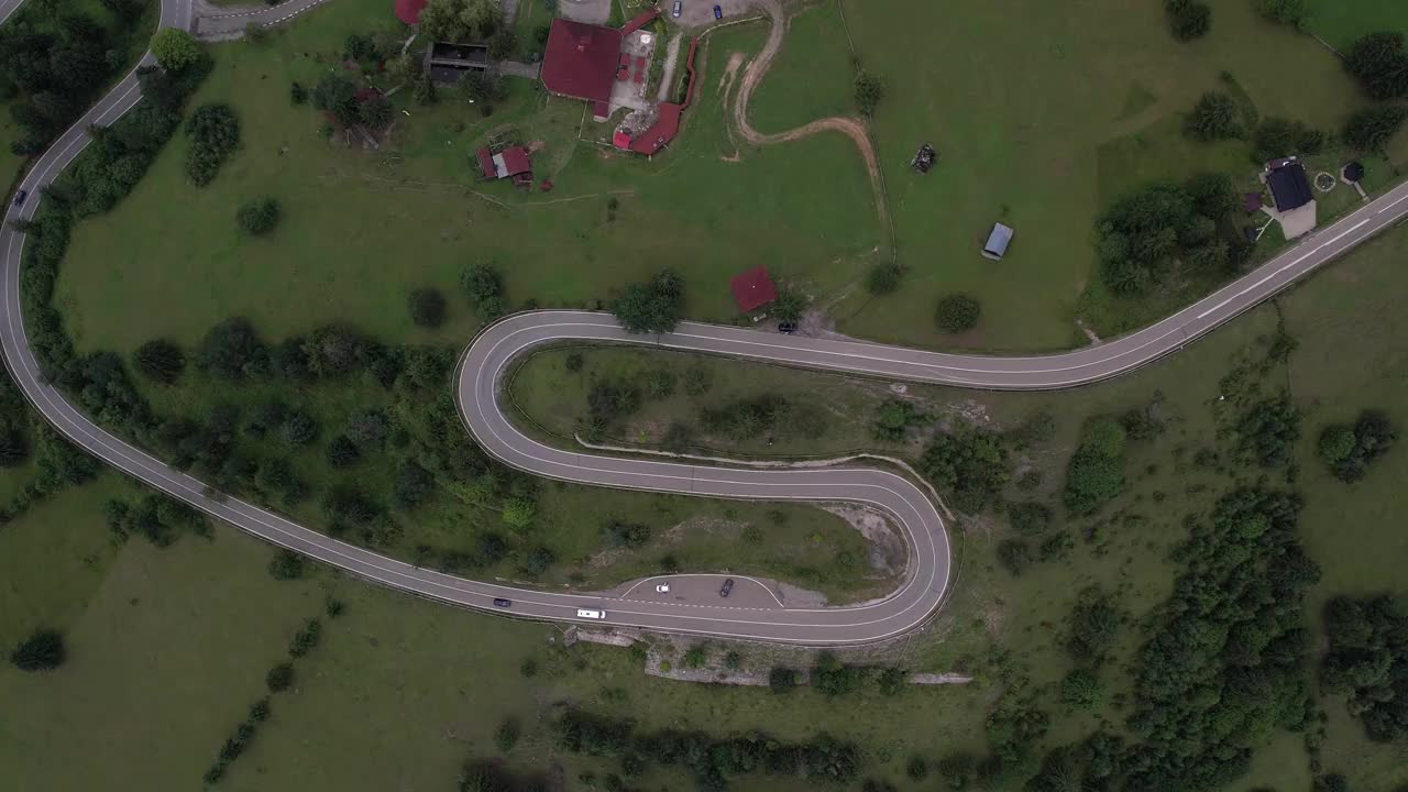 弯弯曲曲的柏油路上山林夏日。
鸟瞰图的道路穿过山和绿色的森林。视频下载