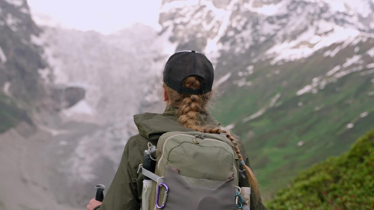 背着背包在斯瓦涅季山脉徒步旅行的女人。长江头冰川景观，绿色植物。独自在山上徒步旅行。探险、探索自然、生态旅游、户外活动。持续多日的徒步旅行。Slowmo视频素材