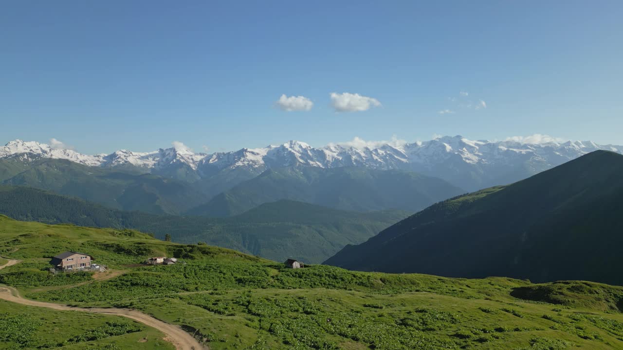 在斯瓦涅季山脉的高山草地上徒步旅行的孤独旅行者鸟瞰图。一个人走在白雪皑皑的翠绿山间。探险旅游，自然探险。无人机拍摄的视频素材