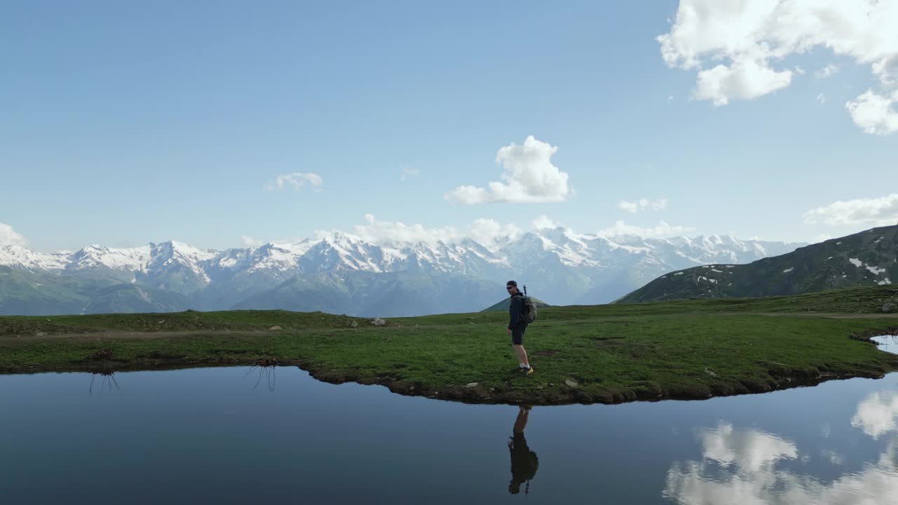 航拍照片，徒步旅行者背着背包在斯瓦涅季山脉的Koruldi湖边散步。独自徒步者探索大自然，高山风景倒映在水中。探险旅行，户外活动，在乔治亚州徒步旅行。视频素材