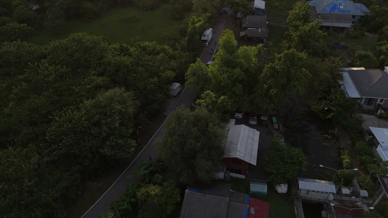 鸟瞰图，一个郊区社区被郁郁葱葱的绿色植物包围，远处的山脉和戏剧性的日落天空。视频下载