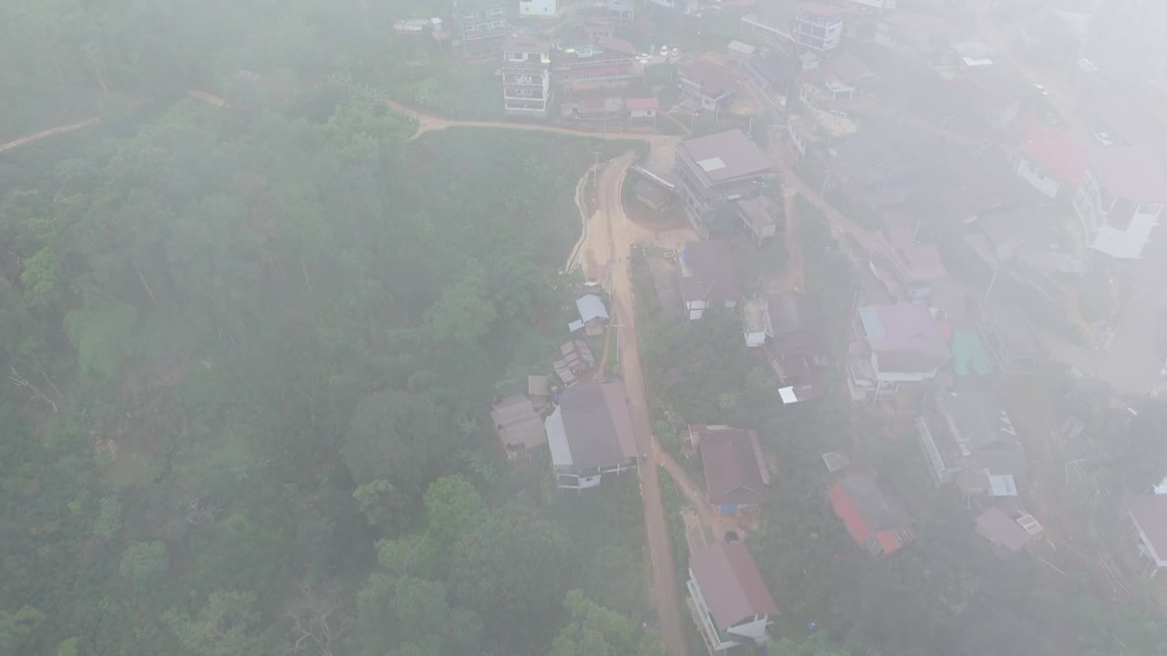 空中拍摄的雾气笼罩的山村，绿草如茵，道路蜿蜒，房屋四散。视频下载