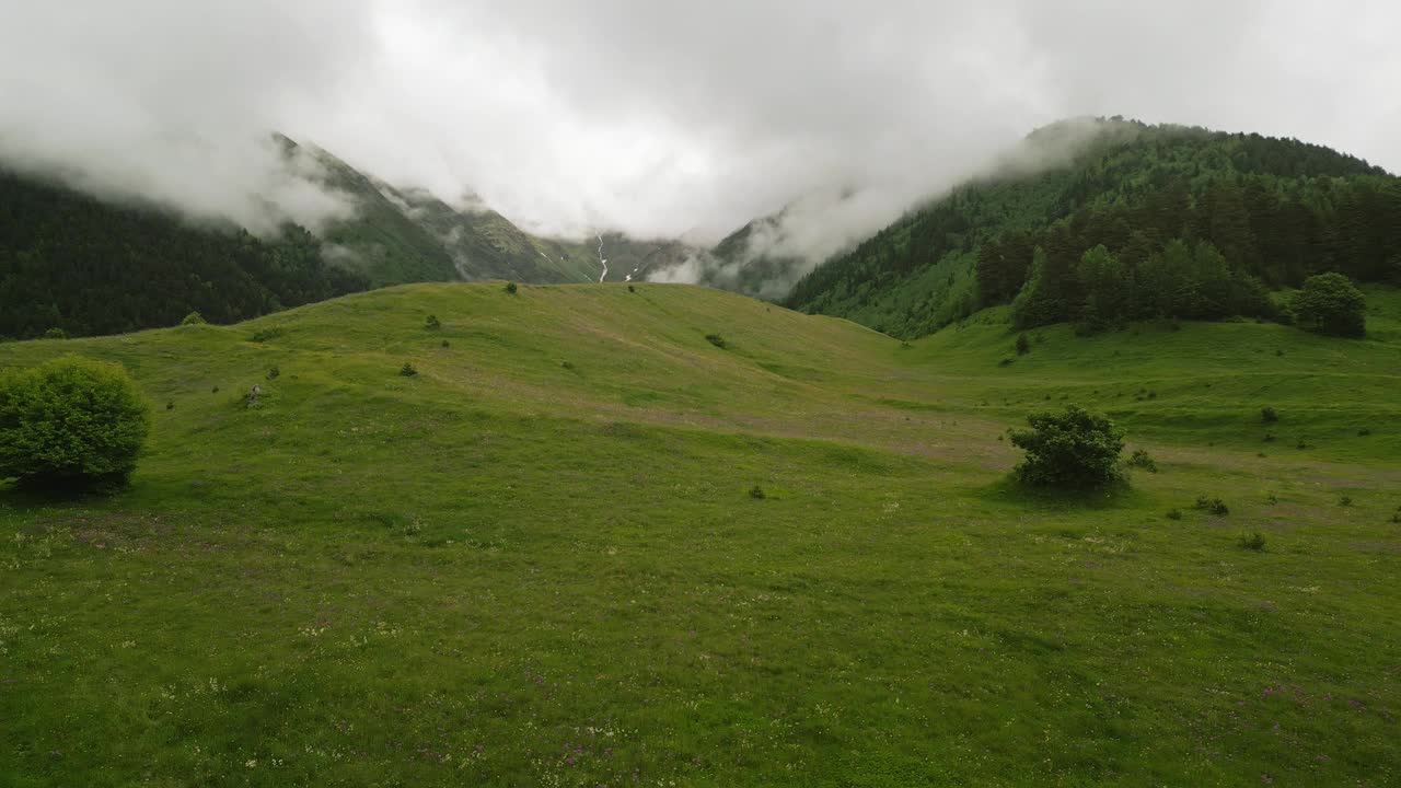 男子在斯瓦涅季山脉的高山草地上徒步旅行。徒步旅行者探索绿色的风景与雾蒙蒙的山峰，郁郁葱葱的树木。在风景优美的乡村探险、旅行和享受大自然。格鲁吉亚的旅游和户外活动。视频素材