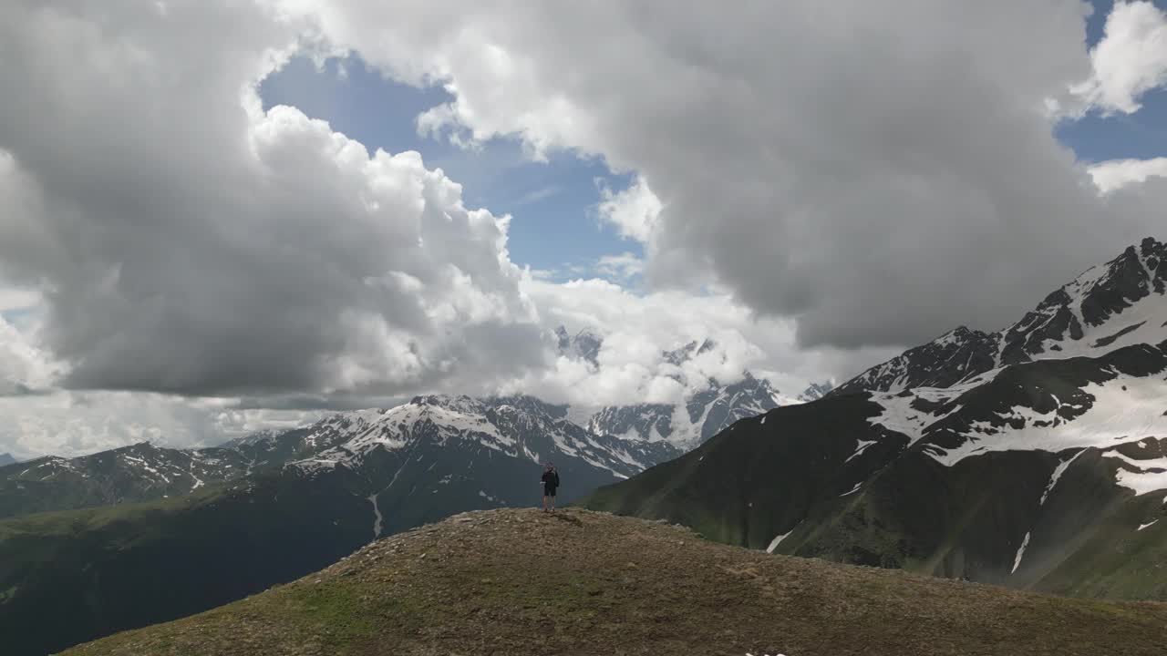 背包客欣赏斯瓦涅季山脉的景色。旅行者登上山顶，四周是白雪皑皑的山峰，云雾缭绕。风景，冒险，自由。大自然，徒步旅行，在乔治亚州旅行，探索荒野。视频素材