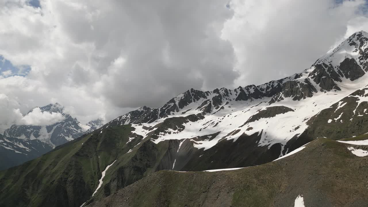 高加索山脉在斯瓦涅季的鸟瞰图，白雪皑皑的山峰，绿色的山谷。山脊上孤零零的人影。多云的天空。风景优美，适合旅行、探险、徒步旅行、自然纪录片。无人机视频素材