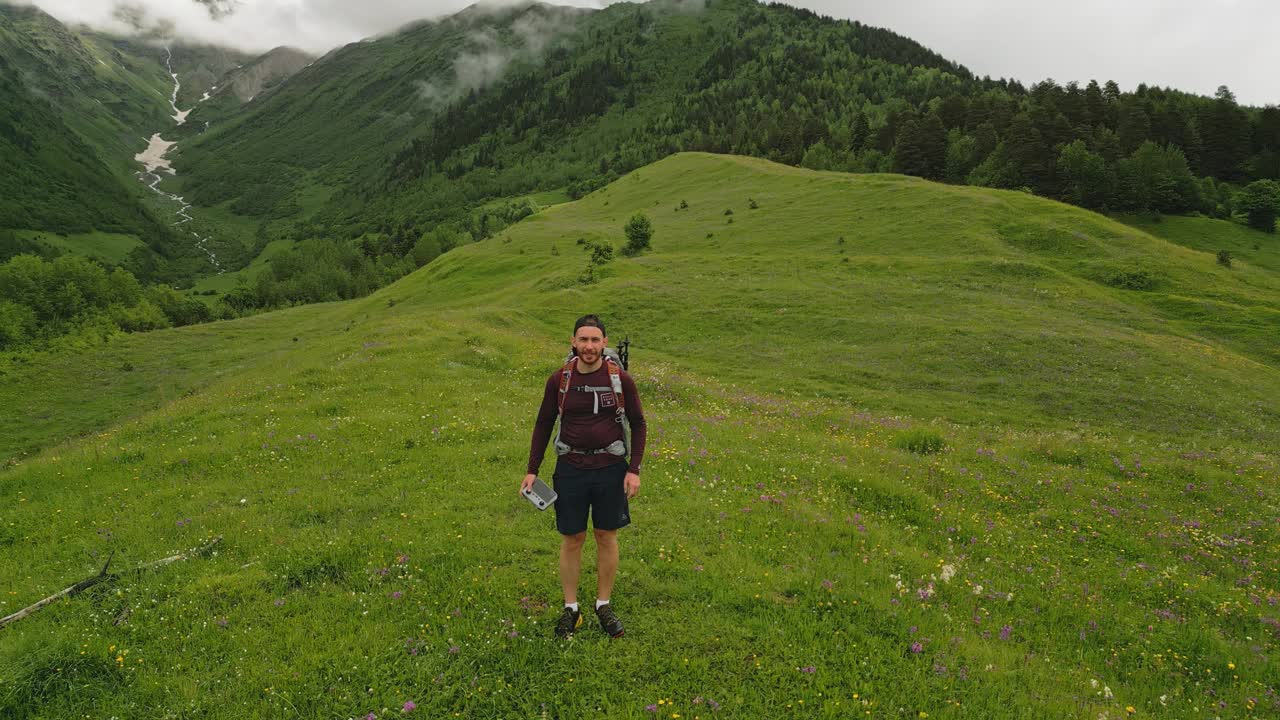 独自旅行的背包客徒步登山高山草地。享受美景，自由。空中自拍，青山葱茏，山水宁静，云淡风轻。徒步探险，自然探险。独自旅行。无人机拍摄的视频素材