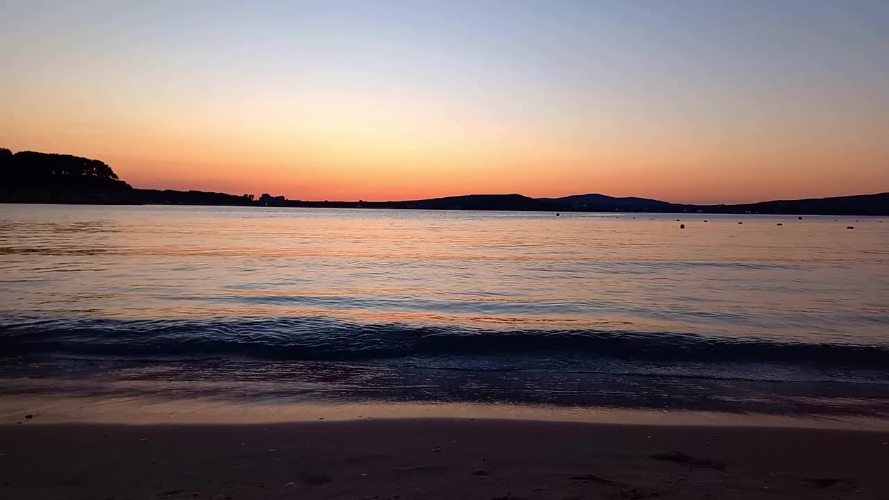 夏天海上美丽的日落。沙滩，平静的大海。保加利亚黑海海岸风景如画的日落。绚丽多彩的天空。海上浪漫的夜晚视频素材